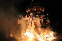 白い衣装を着て神輿を担いだ人達が、火の上を歩いている写真