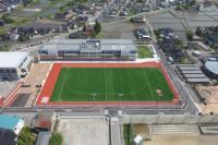 校舎と緑色の広い運動場を上空から写した写真
