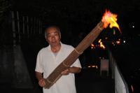 年配の男性が火が灯った大きな松明を持っている写真