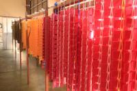 赤やオレンジ色の編み上げられた沢山のかんもちが棒から吊るされている写真