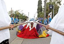 獅子舞が2本の長い棒で威嚇されている祭りの様子の写真