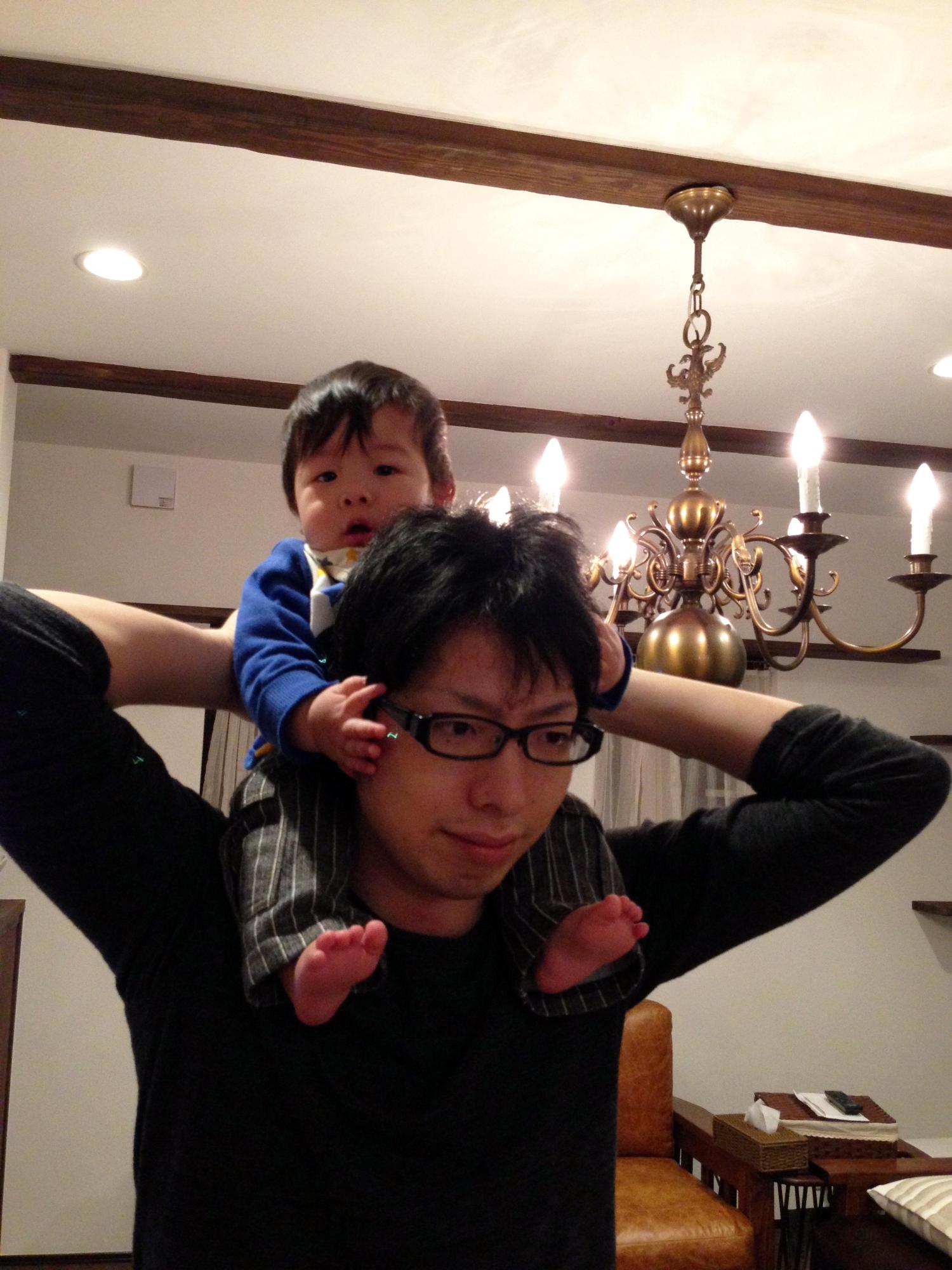 高江さんが赤ちゃんを肩の上に座らせて肩車をしている父子写真