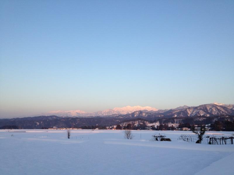 遠くには山々が連なり、真っ白な雪が降り積もった富山平野の風景写真