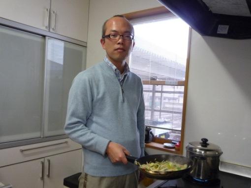 フライパンで野菜を炒めているお父さんの写真