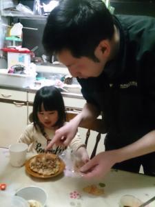 テーブルに座っている女の子と、テーブルに置かれた食べ物を指さしているお父さんの写真