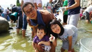 大勢の人が水の中に入っている中に写っている子供達2人とお父さんの写真