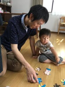 男の子と一緒にパズルをしているお父さんの写真