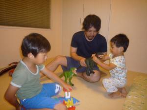 恐竜のおもちゃで子供と一緒に遊んでいるお父さんの写真