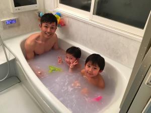 お父さんと男の子2人が湯船に浸かっている写真