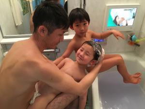 お父さんが男の子を膝の上に乗せて男の子の頭を洗っている写真