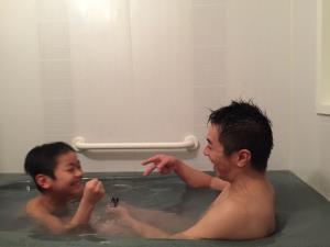 男の子とお父さんがお風呂の湯舟に入って楽しそうにしている写真