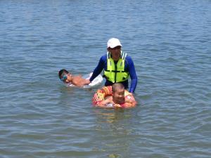 浮き輪を使って水の中で遊んでいる男の子2人とお父さんの写真