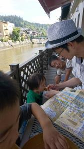 川が見えるテラスのような場所で、男の子に食べ物を食べさせているお父さんの写真