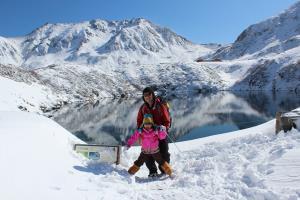 雪山にある湖の前に立っている女の子とお父さんの写真