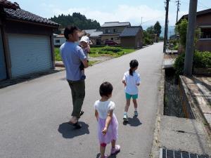 赤ちゃんを抱っこし、女の子2人と散歩をしているお父さんの写真