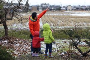 お父さんが指を指している方を見ている子供達2人の写真