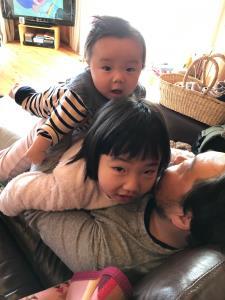 ソファーに座っているお父さんが子供二人を抱っこしている写真