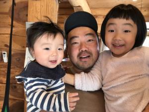 両腕に子供達を抱っこしているお父さんの写真