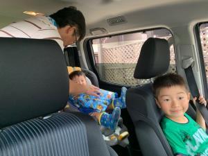 助手席に乗っている男の子と、チャイルドシートに男の子を乗せているお父さんの写真