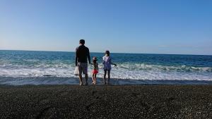 浜辺に立っている子供達2人とお父さんの写真