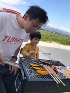 男の子と一緒にバーベキューコンロで調理をしているお父さんの写真