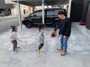 子供達と一緒に縄跳びをしているお父さんの写真