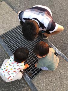 双子の子供達と一緒に用水路の中を覗き込んでいるお父さんの写真