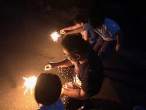 子供達3人と一緒に花火をしているお父さんの写真