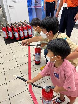 男の子2人と一緒に家事の消火体験をしているお父さん