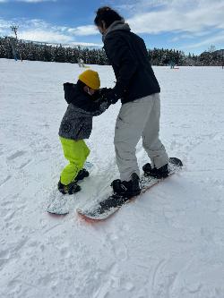 子どもと一緒にスノーボードを楽しんでいるパパ