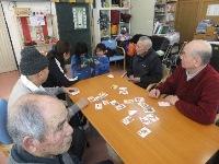 年配の男性4人と園児2人がカードゲームをしている写真