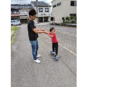 スケボーをしている子どもの手を支えるお父さん