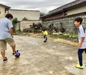 お父さんと男の子2人の兄弟が外でサッカーをしている